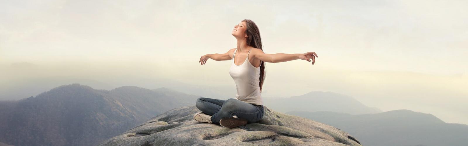Девушка медитирует на вершине горы